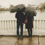 man and woman holding black umbrellas