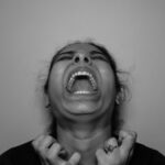 a woman with her mouth open and hands in front of her face