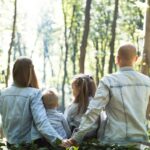 man and woman holding hands together with boy and girl looking at green trees during day